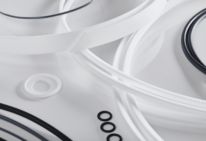 White polymer seals, gaskets, and O-rings arranged to represent precision components used in fluid management equipment for sealing, flow control, and leak prevention.